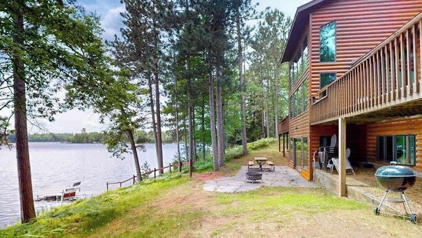Una baita con veranda che si affaccia su un lago, un barbecue e un braciere.