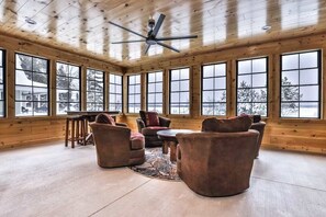A spacious room with large windows, wooden walls, and a ceiling fan.