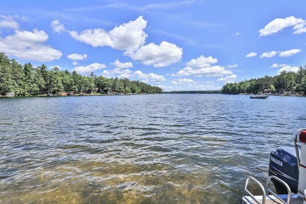 A lake with a boat, clear water, and a forested shoreline.