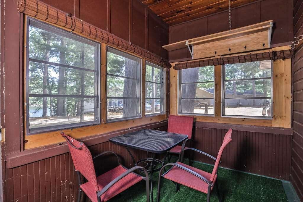 A room with a table and chairs, large windows, and wooden walls.