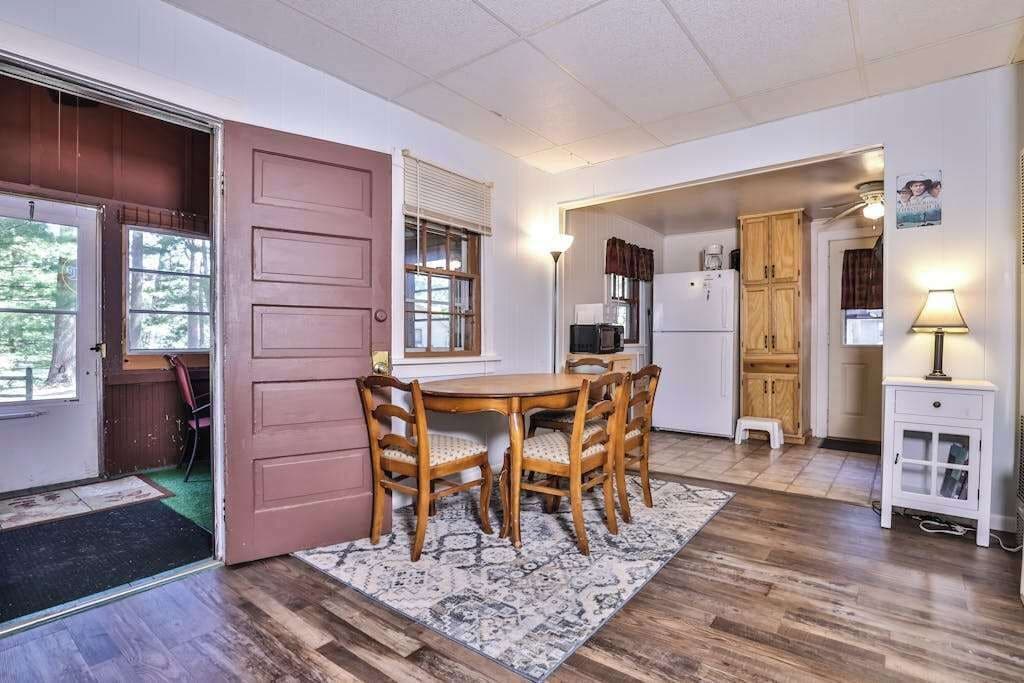 A dining area with a wooden table and chairs, a kitchen with cabinets and appliances, and a door leading to another room.