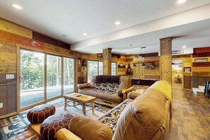 Ein gemütliches Interieur mit Holzwänden, großen Fenstern und einer Sitzecke mit Sofas und einem Couchtisch.