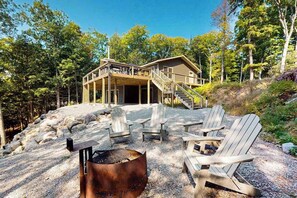 Eine Hütte mit einer Terrasse, Sitzgelegenheiten im Freien und einer Feuerstelle.