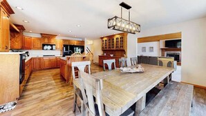 A kitchen with wooden cabinets, a dining table, and a chandelier. - Dog-friendly lodging w/ scenic deck, pool table, lake dock, & free WiFi (St. Germain)
