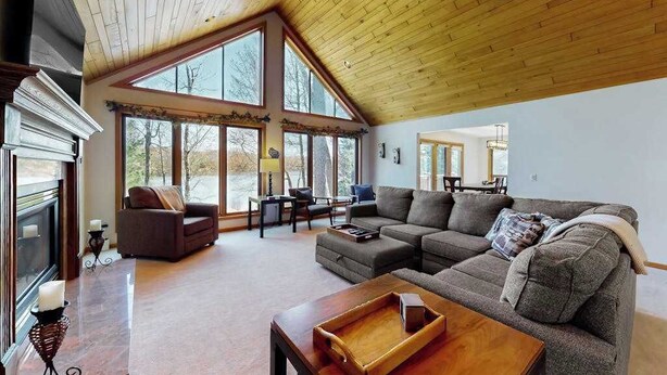 A spacious living room with a large sectional sofa, a wooden coffee table, and a fireplace. - Dog-friendly lodging w/ scenic deck, pool table, lake dock, & free WiFi (St. Germain)