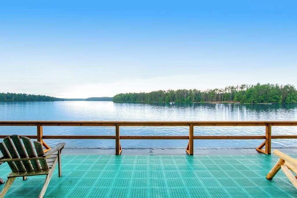 A deck with a view of a calm lake and forested land.