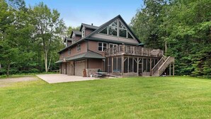 A two-story house with a covered porch and a staircase leading to a deck. - Large, waterfront home w/ a full kitchen, dock, canoes, & outdoor firepit (Tomahawk)