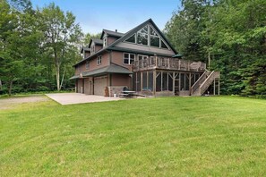 A two-story house with a covered porch and a staircase leading to a deck. - Large, waterfront home w/ a full kitchen, dock, canoes, & outdoor firepit (Tomahawk)