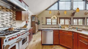 A kitchen with a large stove, dishwasher, wooden cabinets, and a window with a view. - Large, waterfront home w/ a full kitchen, dock, canoes, & outdoor firepit (Tomahawk)
