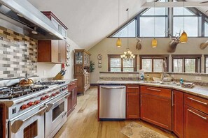 A kitchen with a large stove, dishwasher, wooden cabinets, and a window with a view. - Large, waterfront home w/ a full kitchen, dock, canoes, & outdoor firepit (Tomahawk)