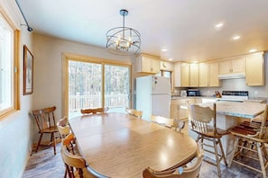 A kitchen with a dining table, chairs, a refrigerator, and a microwave. - Cozy tree-lined home located near town, lakes, walking & bike trails, w/ firepit (Manitowish Waters)