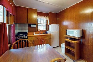 Una cocina compacta con armarios de madera, estufa, microondas y una mesa de comedor.