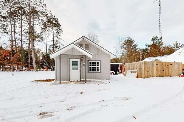 A small, single-story building with a gabled roof, a front door, and a window. - Dog-friendly, tree-lined home on the snowmobile trail with streaming, W/D, & AC (Manitowish Waters)