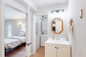 A bedroom with a bed, a bathroom with a sink and mirror, and a laundry area with a washing machine. - Dog-friendly, tree-lined home on the snowmobile trail with streaming, W/D, & AC (Manitowish Waters)