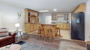 Une cuisine moderne avec des meubles en bois, un réfrigérateur noir et un îlot central doté de tabourets.
