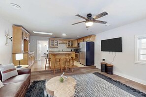 A modern kitchen with wooden cabinets, a central island with stools, a large refrigerator, and a ceiling fan. - Dog-friendly, tree-lined home on the snowmobile trail with streaming, W/D, & AC (Manitowish Waters)