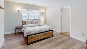 Une chambre à coucher avec un lit, une table de chevet, une fenêtre et une porte.