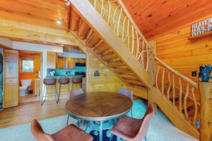 Ein Holzinterieur mit Treppe, einem runden Esstisch und Barhocker.