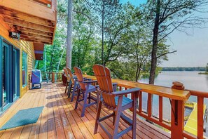 Eine Holzterrasse mit Stühlen und einem Tisch, mit Blick auf einen See.