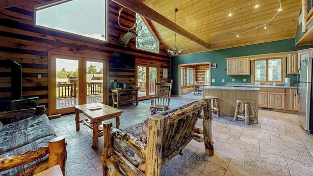 L’intérieur d’un chalet rustique comprend un coin repas, une cuisine et de grandes fenêtres.