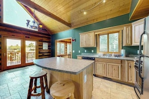 A kitchen with wooden cabinets, a granite countertop, and a large island with stools. - Cozy Home located on the Turtle Flambeau Flowage, great for all seasons! (Mercer)