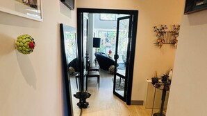 Ein Flur mit einer Holztreppe, einem Spiegel und einer Tür zu einem Zimmer mit Blick.