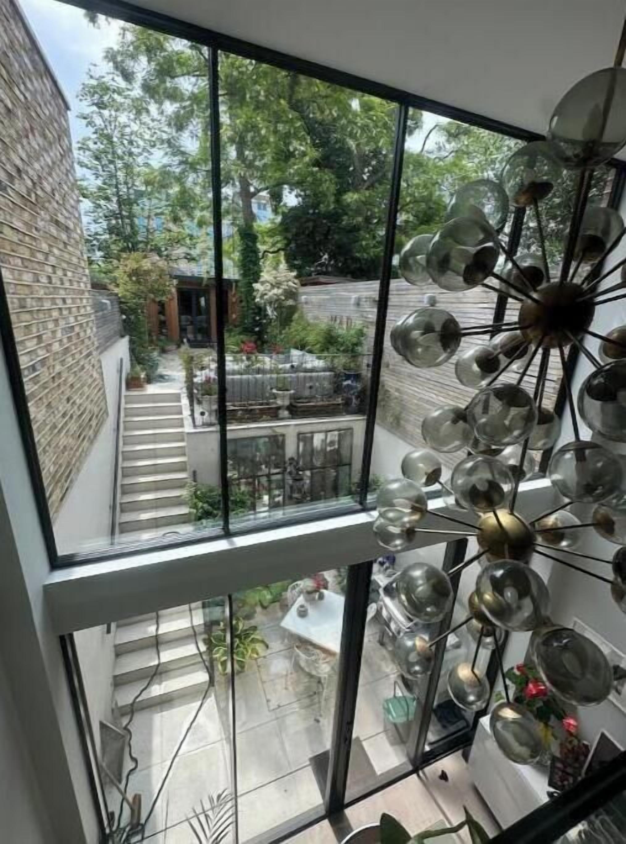 Un intérieur moderne avec de grandes fenêtres, un plafond en verre et un luminaire décoratif.