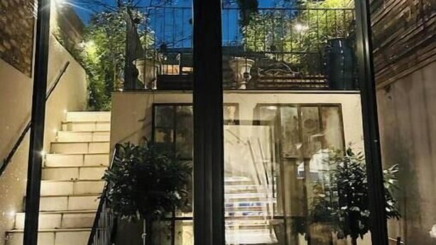 Ein modernes Gebäude mit Glasfassade, einer Treppe und Pflanzen im Außenbereich.