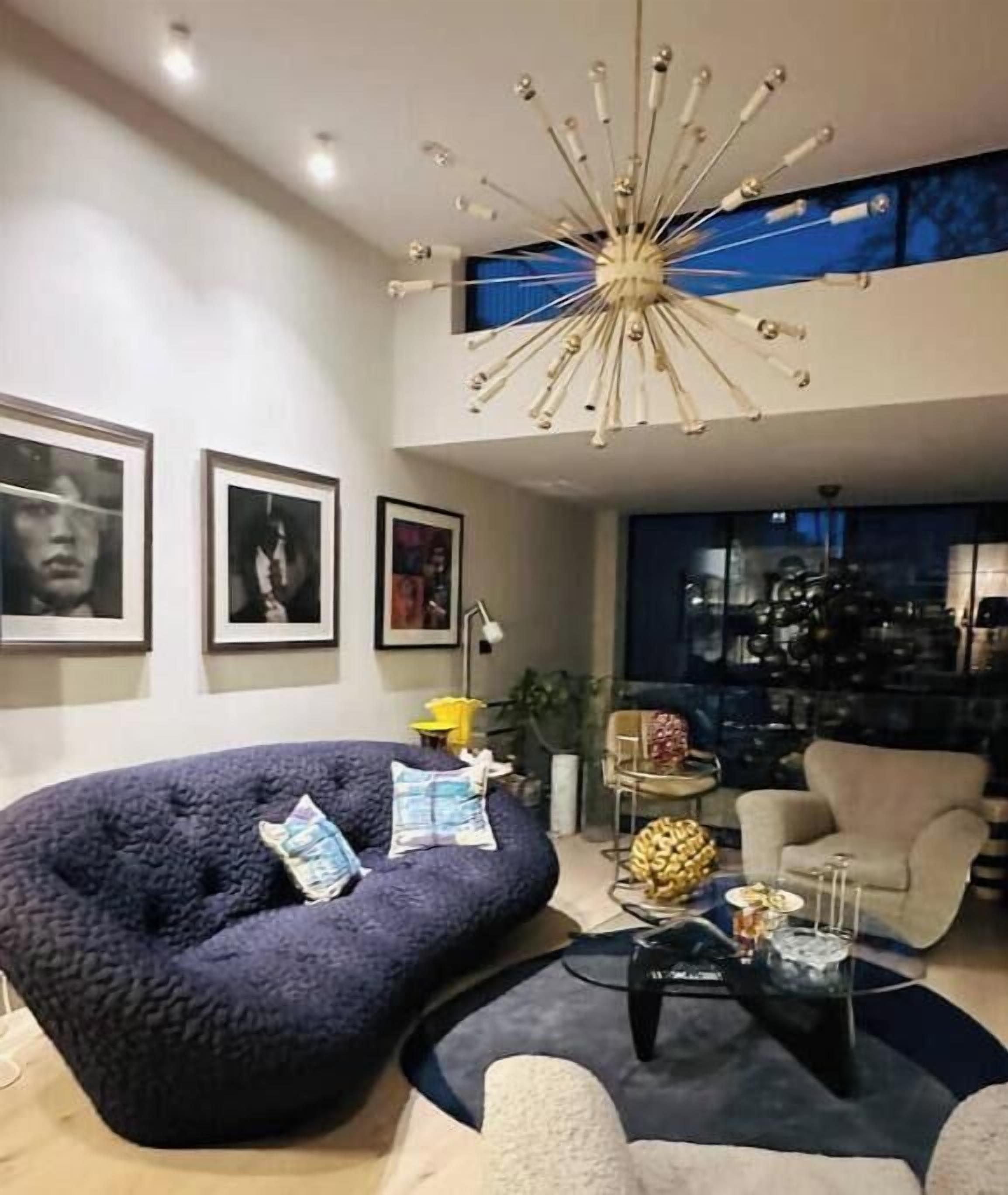 Ein modernes Wohnzimmer mit einem blauen Sofa, einem Couchtisch und einer außergewöhnlichen Deckenleuchte.