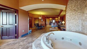 A spacious bathroom with a large bathtub, a wooden door, and a tiled wall. - Wisconsin Dells Escape | Adventure Perks Included (Wisconsin Dells)