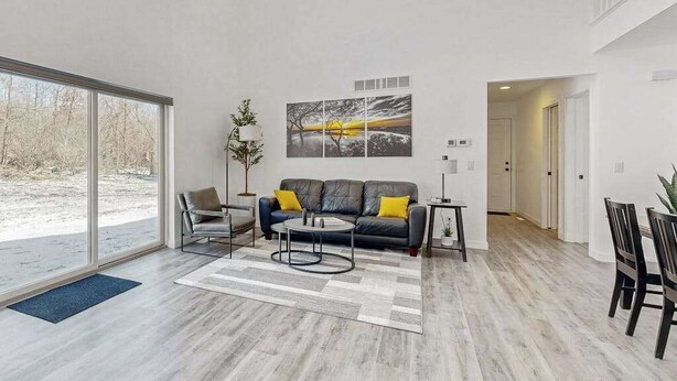 Ein modernes Wohnzimmer mit Sofa, Couchtisch und einem großen Fenster.