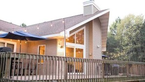 Une maison avec une terrasse, de grandes fenêtres et une cheminée.