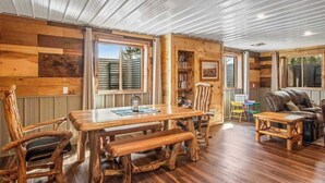 Un interior de madera con una mesa de comedor, sillas, un sofá y una estantería.