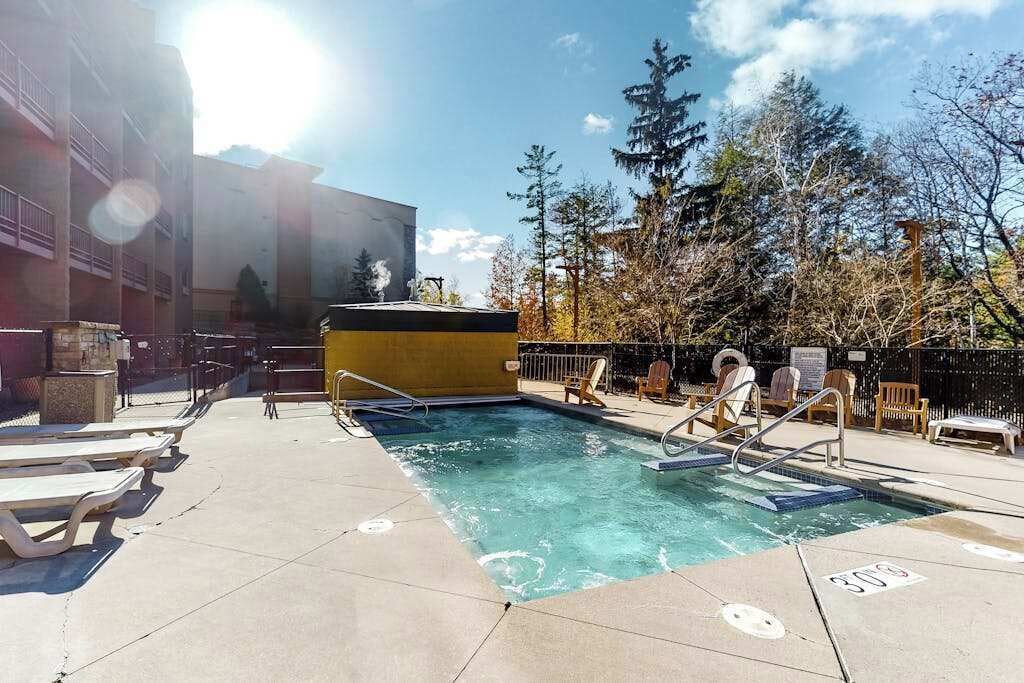A pool area with lounge chairs, a pool, and a building in the background.