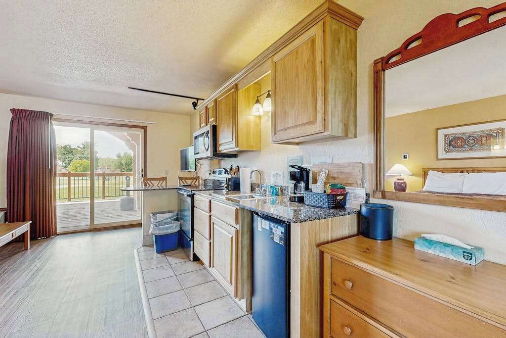 A kitchen with wooden cabinets, a microwave, a coffee maker, and a sink.