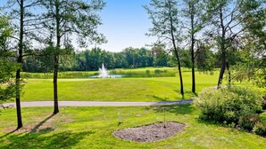 A golf course with a pond, trees, and a path. - Golf course-front home with 2 pools, private beach, boat launches, tennis, grill (Nekoosa)
