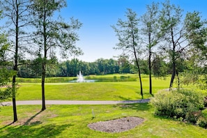 A golf course with a pond, trees, and a path.