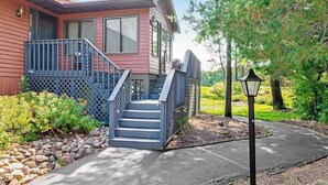 A two-story house with a porch, a staircase, and a pathway leading to a gazebo. - Golf course-front home with 2 pools, private beach, boat launches, tennis, grill (Nekoosa)
