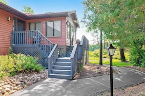 A two-story house with a porch, a staircase, and a pathway leading to a gazebo.