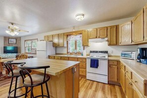 A kitchen with wooden cabinets, a central island, a stove, and a refrigerator. - Cozy wooded duplex w/ WiFi, full kitchen, shared W/D & near lakes & trails (Arkdale)