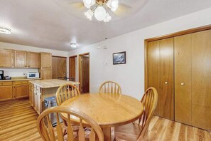 A dining area with a wooden table and chairs, a microwave, and wooden cabinets. - Cozy wooded duplex w/ WiFi, full kitchen, shared W/D & near lakes & trails (Arkdale)