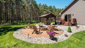 Une terrasse avec des meubles d’extérieur, un foyer et un gazebo en bois.