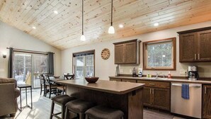 Une cuisine spacieuse avec des meubles en bois, un grand îlot central doté de tabourets et un coin repas offrant une vue agréable.