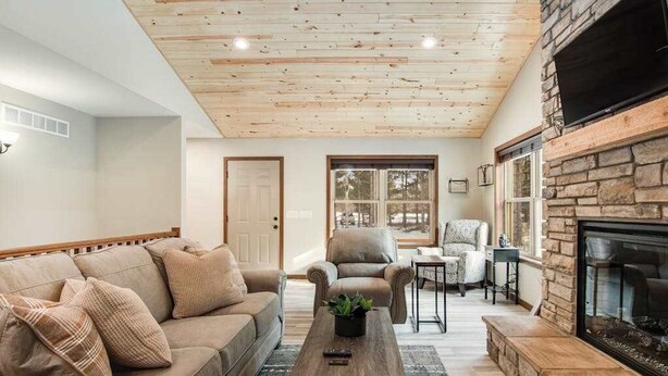 Un salon chaleureux avec un plafond en bois, une cheminée en pierre, un canapé et une table basse.