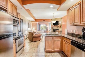 A spacious kitchen with wooden cabinets, a central island, and a stone fireplace. - Stay at Chula Vista | Adventure Awaits Nearby (Wisconsin Dells)