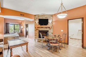 A room with a stone fireplace, a flat-screen TV, a dining table with chairs, and a view of the outdoors. - Stay at Chula Vista | Adventure Awaits Nearby (Wisconsin Dells)