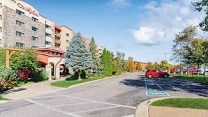 A hotel with a stone facade, a parking lot with marked handicapped spaces, and a red car parked in the lot. - Lovely Studio + balcony + Perks (Wisconsin Dells)