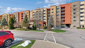 Monikerroksinen hotelli, jossa on keskeinen sisäpiha, pysäköintialue ja punainen auto, joka on pysäköity sille varattuun paikkaan.