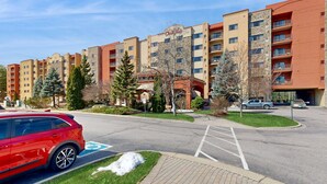Ein mehrstöckiges Hotel mit Parkplatz, einem roten Auto und verschneitem Gelände.