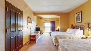 Ein Hotelzimmer mit zwei Betten, einem Schreibtisch, einem Fernseher und einer Tür.